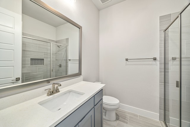 full bathroom featuring a stall shower, baseboards, vanity, and toilet