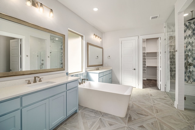 full bath featuring a stall shower, two vanities, a sink, and a freestanding bath