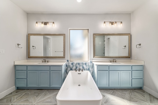 bathroom featuring a sink, baseboards, two vanities, and a freestanding bath