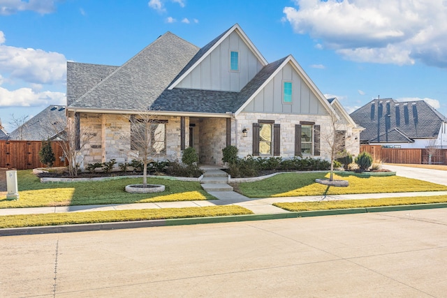 view of front of house with fence, a front lawn, board and batten siding, and roof with shingles