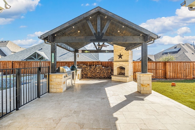 view of patio / terrace with a fenced backyard, an outdoor stone fireplace, exterior kitchen, and a gazebo