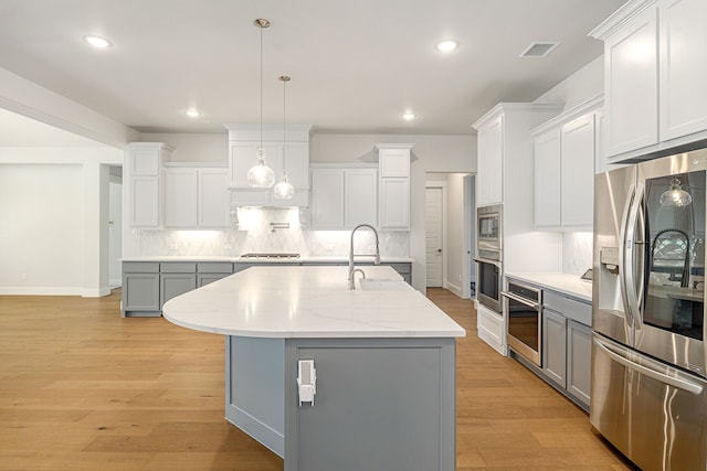 kitchen featuring white cabinets, an island with sink, light wood-style flooring, gray cabinets, and stainless steel appliances