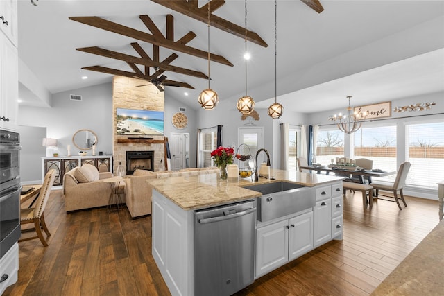 kitchen with a center island with sink, white cabinets, appliances with stainless steel finishes, a fireplace, and a sink