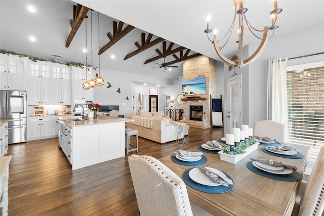 dining room with dark wood-style floors, beam ceiling, a fireplace, and high vaulted ceiling