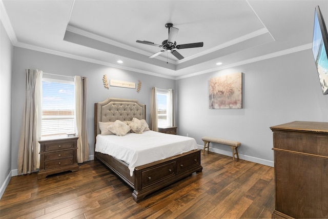 bedroom featuring dark wood-style flooring, a raised ceiling, ornamental molding, ceiling fan, and baseboards