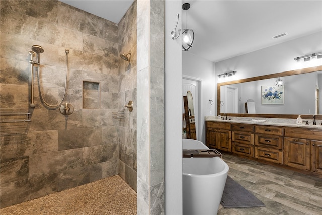 bathroom featuring double vanity, a freestanding bath, a sink, and tiled shower