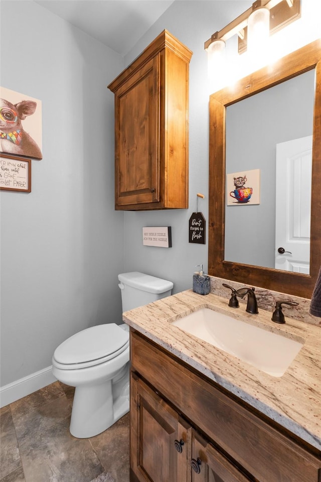 bathroom with toilet, vanity, and baseboards