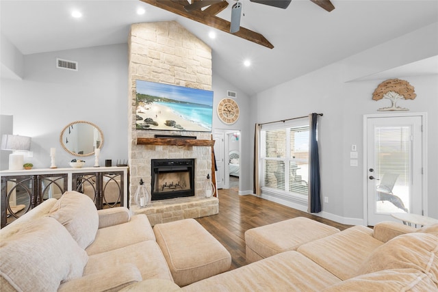 living area with visible vents, a stone fireplace, wood finished floors, high vaulted ceiling, and baseboards