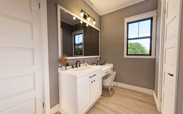 bathroom featuring baseboards, wood finished floors, crown molding, and vanity