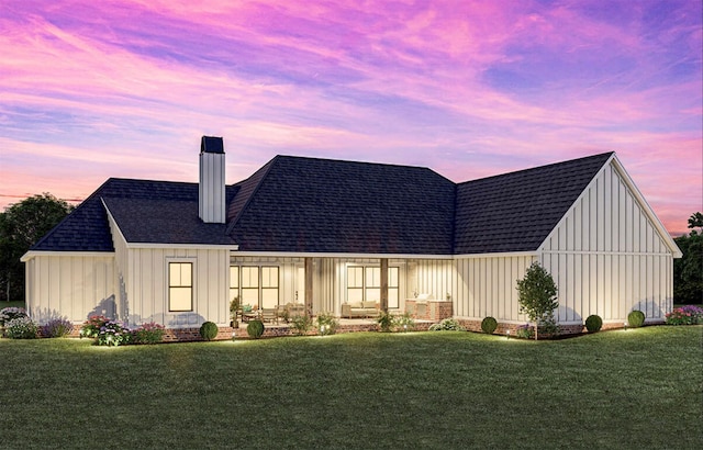 back of property at dusk featuring a yard, board and batten siding, and a chimney