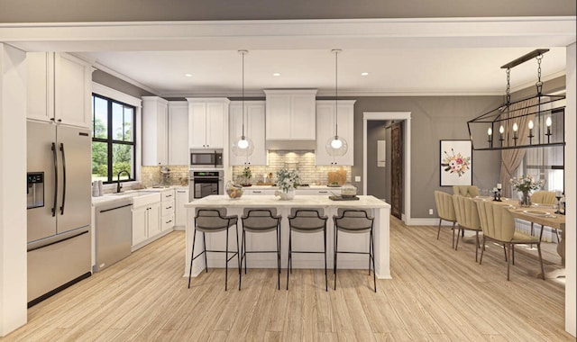 kitchen featuring wall chimney exhaust hood, a kitchen island, stainless steel appliances, white cabinetry, and a sink