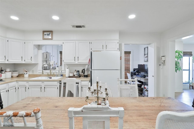 kitchen with white cabinets, light countertops, a sink, and freestanding refrigerator