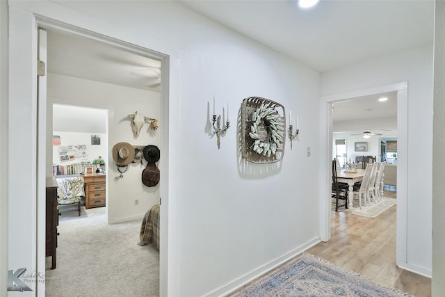 corridor featuring light wood finished floors and baseboards