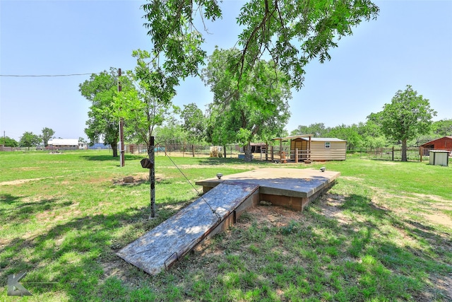 view of property's community featuring a rural view, a lawn, and fence