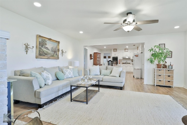 living area featuring light wood-style floors, a ceiling fan, and recessed lighting