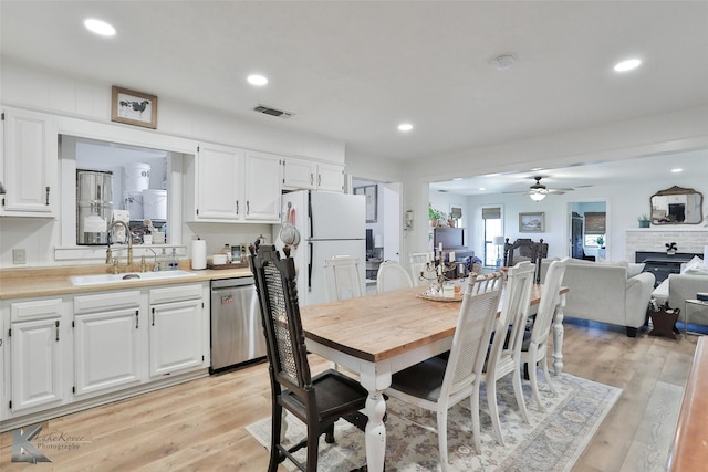 dining room with ceiling fan, recessed lighting, visible vents, light wood-style floors, and a brick fireplace