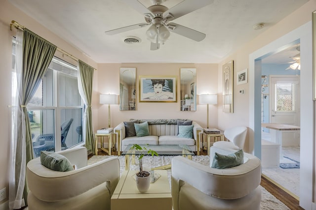 living area with wood finished floors, a ceiling fan, and visible vents