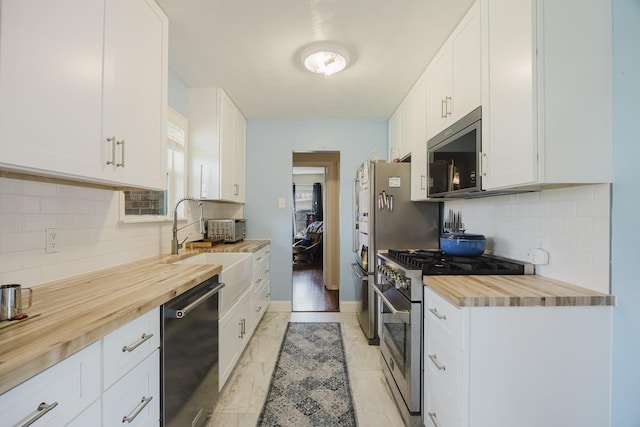 kitchen with white cabinetry, butcher block countertops, appliances with stainless steel finishes, and decorative backsplash