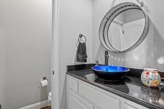 bathroom with toilet, a textured wall, and vanity