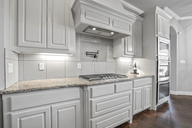 kitchen with custom range hood, decorative backsplash, white cabinetry, and stainless steel appliances