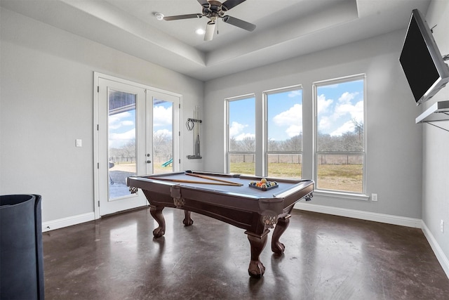 recreation room featuring baseboards, french doors, a tray ceiling, and finished concrete floors