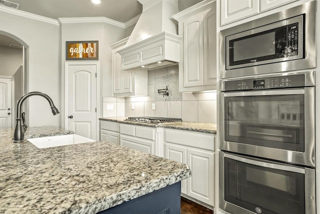 8500 Cobble Stone, Godley, TX 76044 - kitchen with stainless steel appliances, a sink, custom exhaust hood, arched walkways, and crown molding