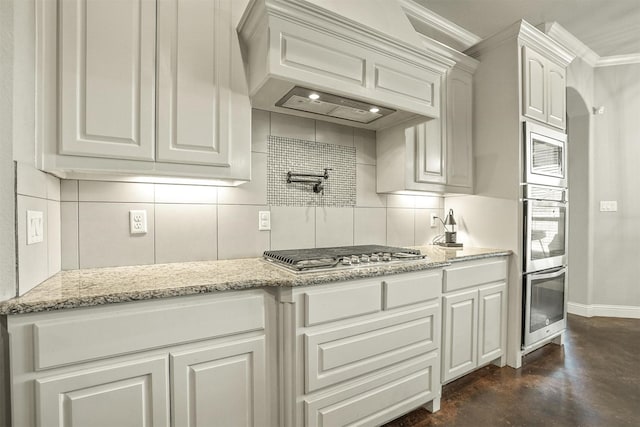 8500 Cobble Stone, Godley, TX 76044 - kitchen with appliances with stainless steel finishes, custom range hood, ornamental molding, light stone counters, and concrete flooring