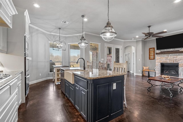 kitchen featuring visible vents, arched walkways, a kitchen island with sink, and concrete flooring