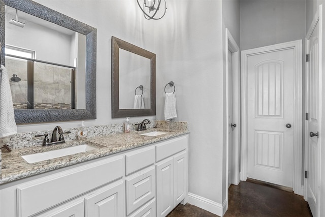 bathroom featuring double vanity, a shower stall, baseboards, and a sink