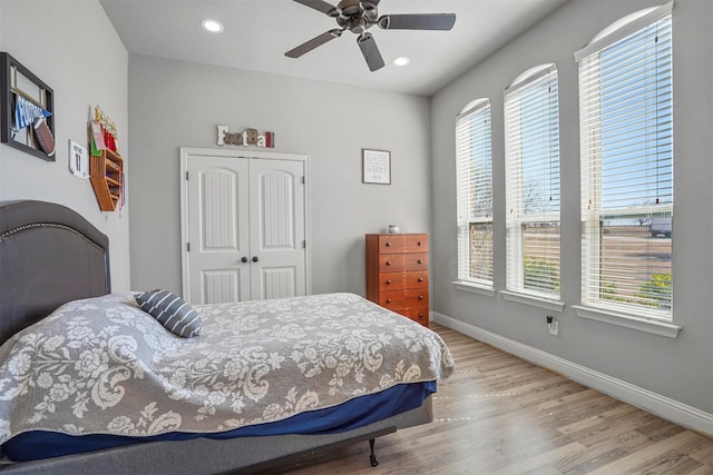 bedroom with recessed lighting, a closet, light wood-style flooring, and baseboards