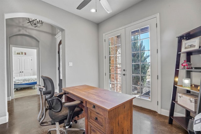 home office featuring ceiling fan, finished concrete flooring, arched walkways, french doors, and baseboards