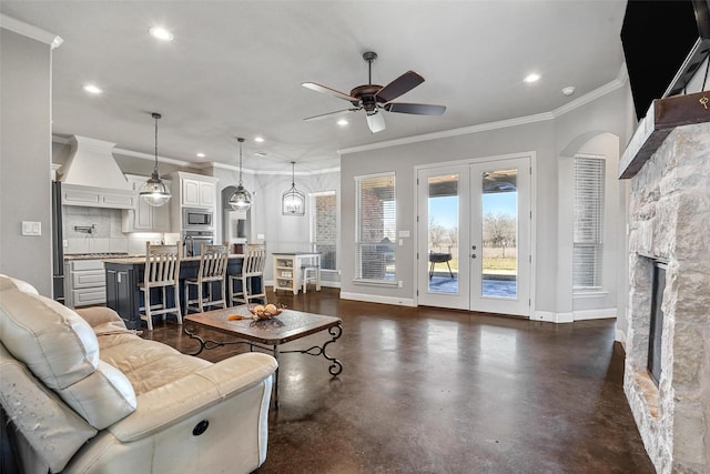 living area with a stone fireplace, concrete floors, recessed lighting, and baseboards