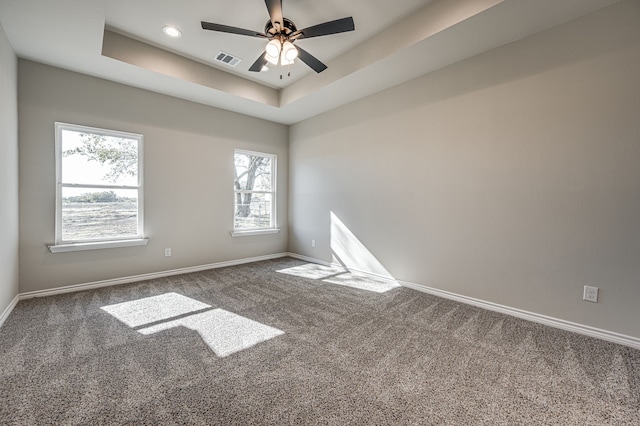 spare room featuring a tray ceiling, baseboards, visible vents, and carpet flooring