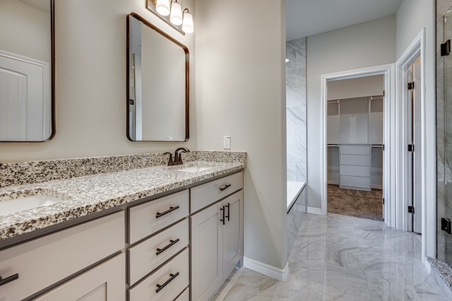 bathroom with a walk in closet, marble finish floor, a sink, and walk in shower