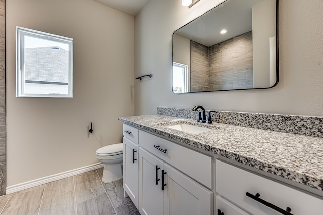 full bath with toilet, baseboards, and vanity