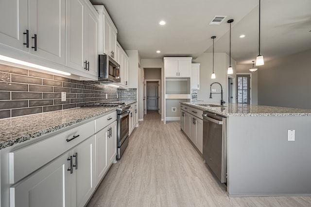 kitchen with visible vents, white cabinets, an island with sink, appliances with stainless steel finishes, and a sink