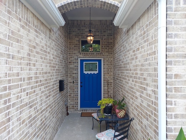 view of exterior entry featuring brick siding