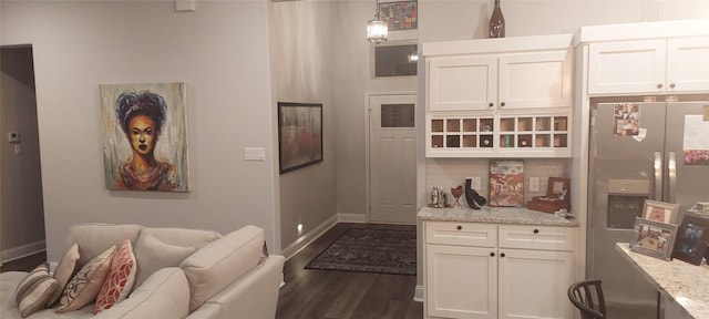 kitchen with white cabinets, decorative light fixtures, stainless steel refrigerator with ice dispenser, and light stone countertops