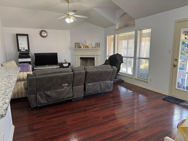 living area with lofted ceiling, ceiling fan, a fireplace, and dark wood finished floors