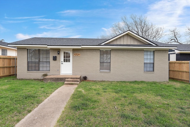 single story home with board and batten siding, fence, and a front lawn