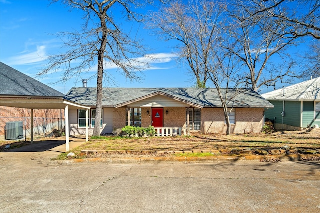 view of front of property with a porch, central air condition unit, brick siding, driveway, and a carport