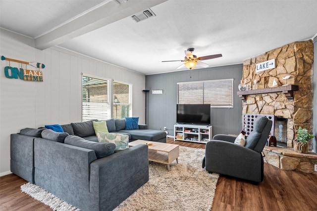 living room with ceiling fan, a fireplace, visible vents, and wood finished floors