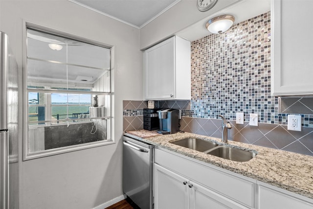 kitchen with stainless steel appliances, tasteful backsplash, white cabinets, a sink, and light stone countertops