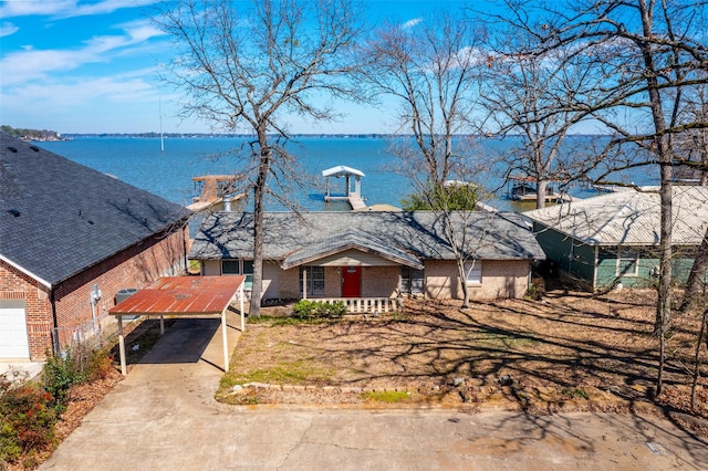 view of front of home with a carport, concrete driveway, a water view, and brick siding