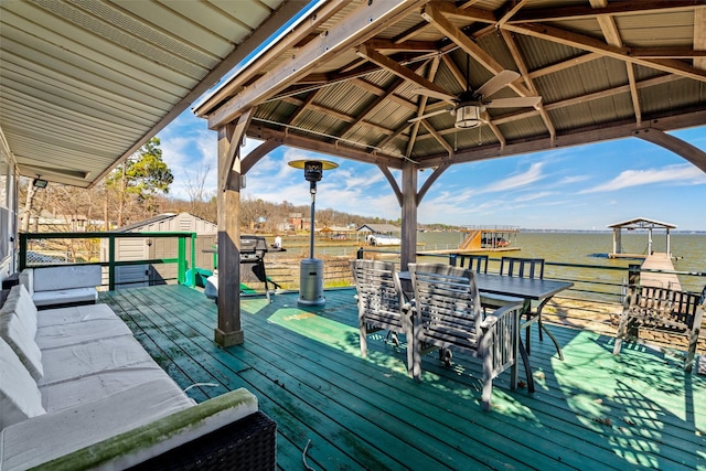 wooden terrace featuring ceiling fan, a storage shed, a water view, an outdoor structure, and a gazebo