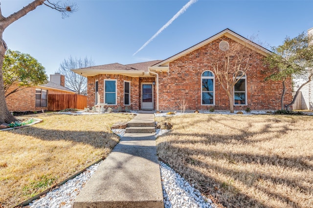 single story home with brick siding, a front yard, and fence