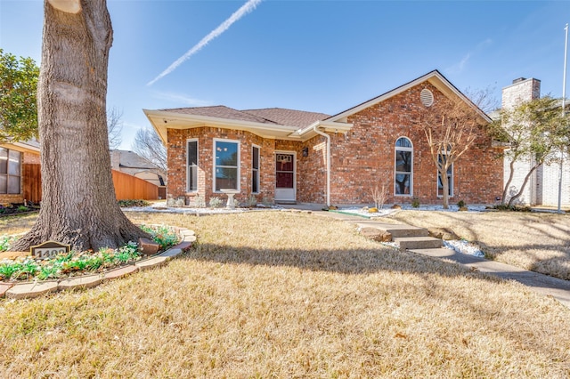 view of front of house featuring brick siding, a front yard, and fence