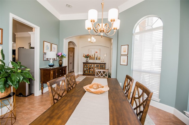 dining area with arched walkways, ornamental molding, visible vents, and a notable chandelier