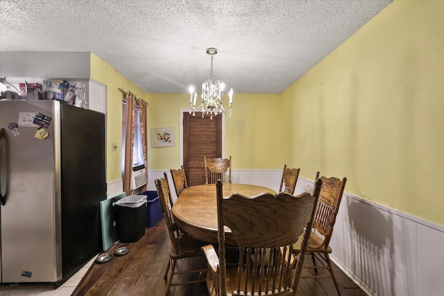 dining room with a wainscoted wall, a textured ceiling, and wood finished floors