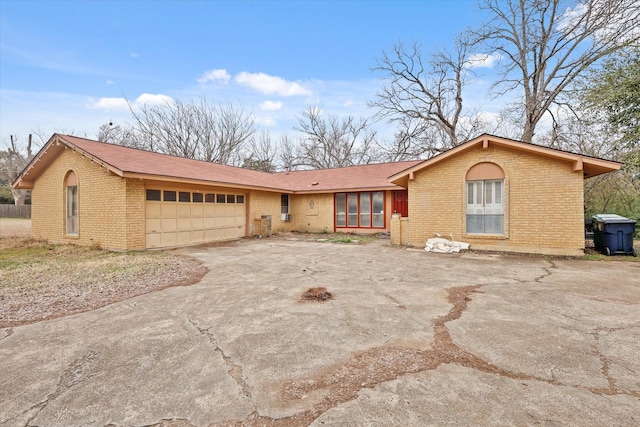 ranch-style home featuring a garage, concrete driveway, and brick siding